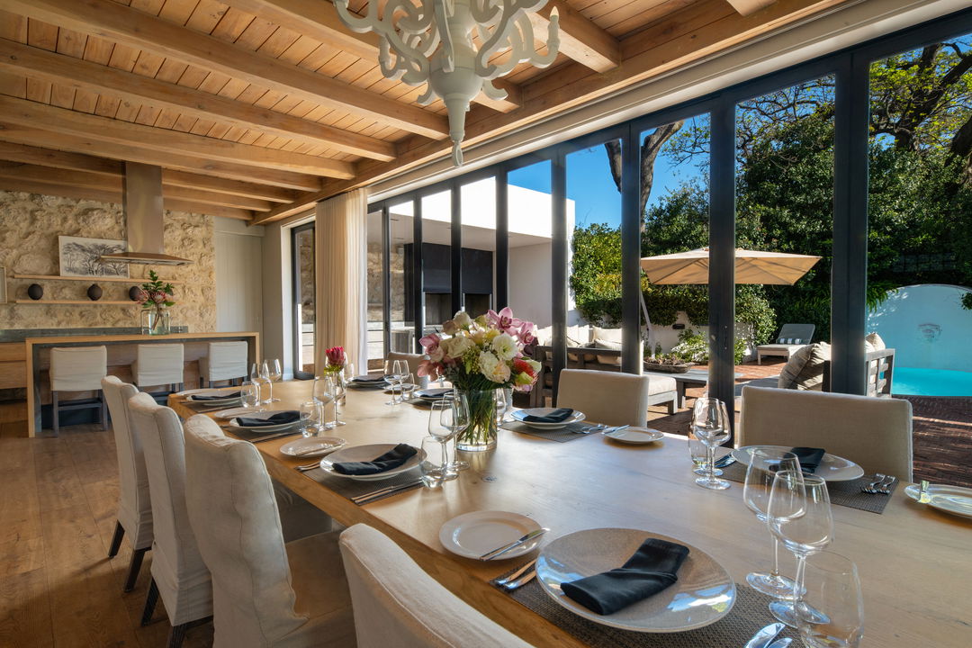 long dining table with chairs set with open sliding windows at Mont Rochelle Luxury Hotel in Franshoek