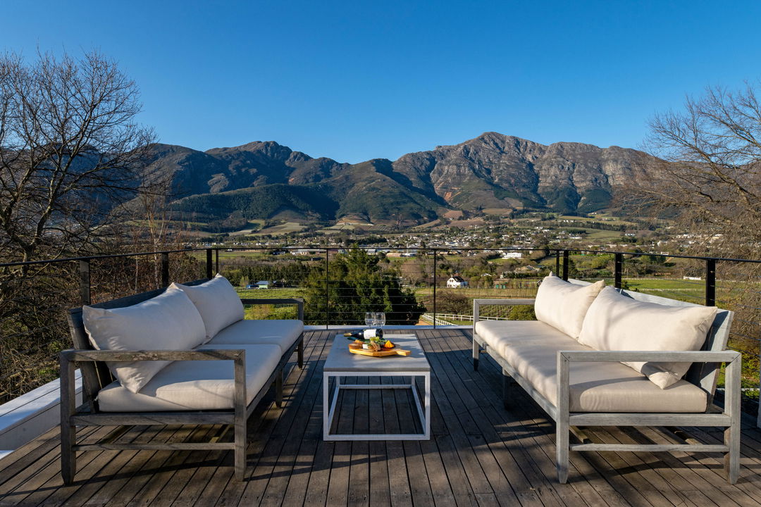 deck with two sofas and table looking at mountain vistas at Mont Rochelle Luxury Hotel in Franshoek