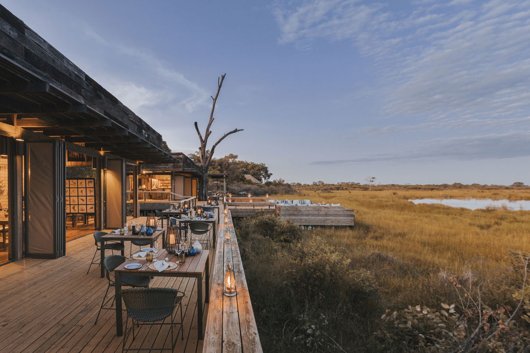 main deck at lodge set up for dinner at sunset at Vumbura Plains Camp Wilderness 