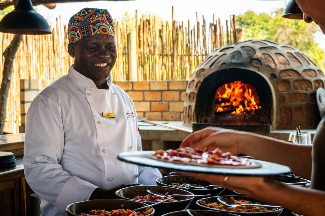 chef serving pizza to guests of Nyamatusi Camps Mana Pools Zimbabwe 