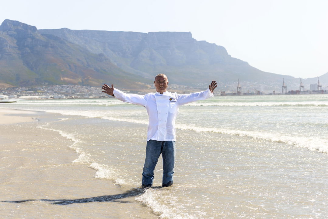 chef on beach with arms outstretched at One&Only Resort Waterfront Cape Town