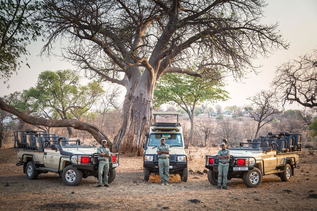 rangers with three safari vehicles posing under a big tree by Puku Ridge Camp Zambia Luangwa Plains