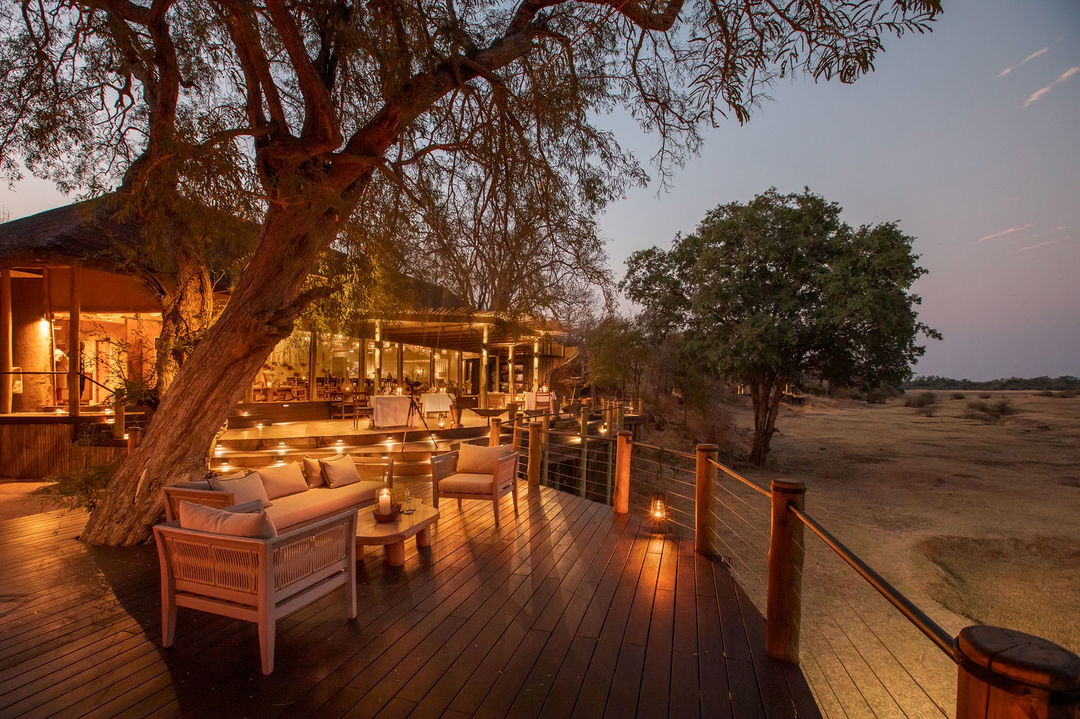 evening view of main deck with tables set for dinner by Puku Ridge Camp Zambia