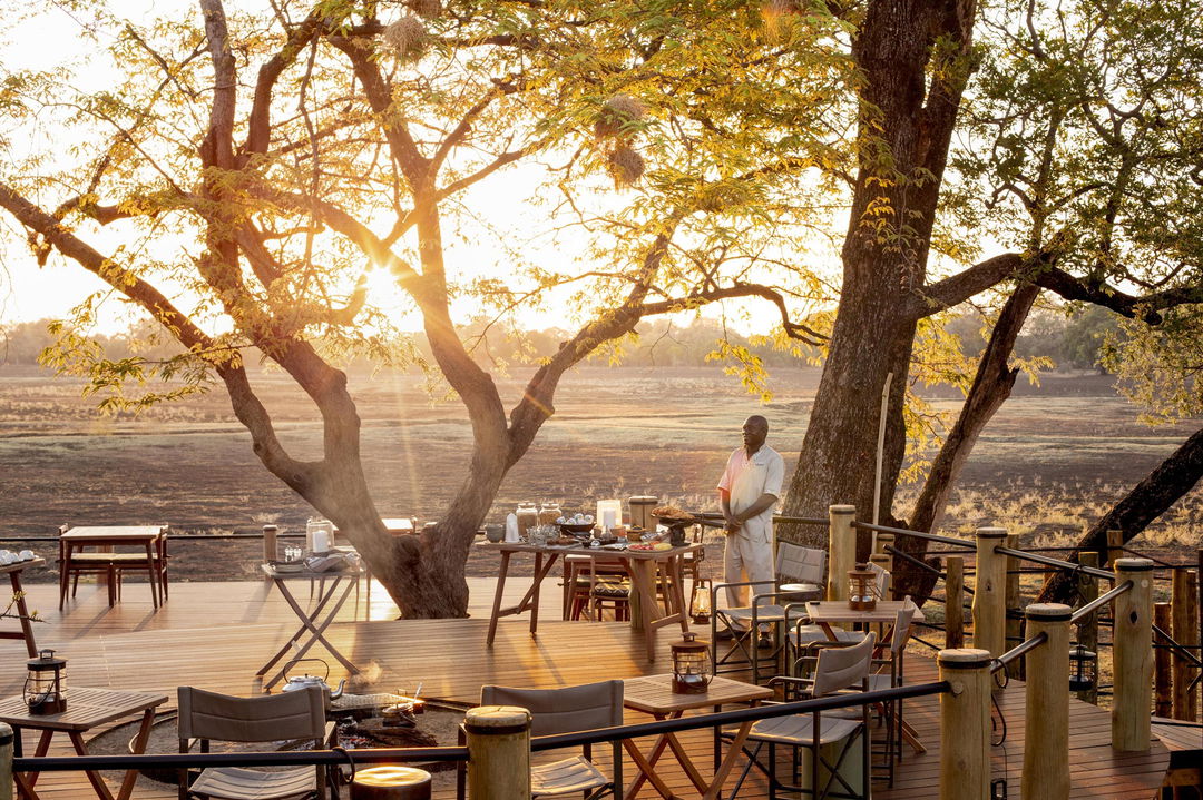 staff preparing breakfast on main deck of lodge by Puku Ridge Camp Zambia