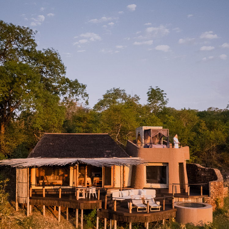 exterior view of tented suite and starbed at sunset by Puku Ridge Camp Zambia