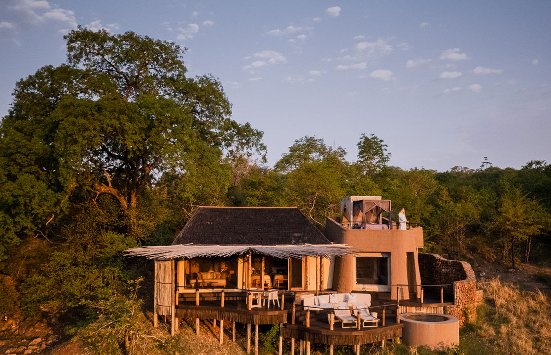 exterior view of tented suite and starbed at sunset by Puku Ridge Camp Zambia