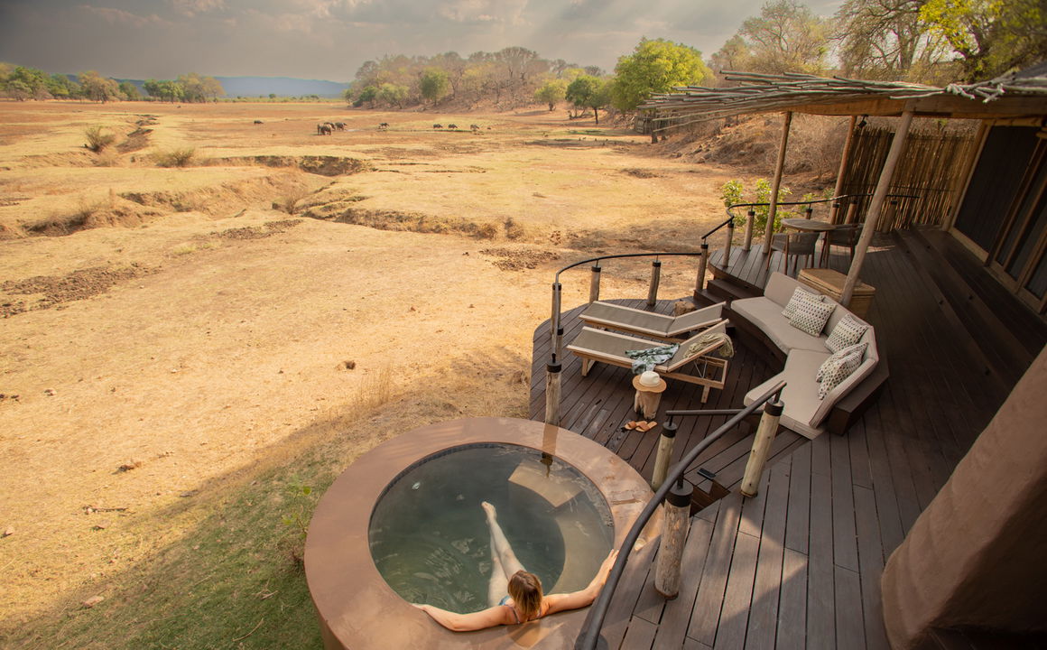 lady guest in splash pool overlooking Luangwa plains of Puku Ridge Camp Zambia 