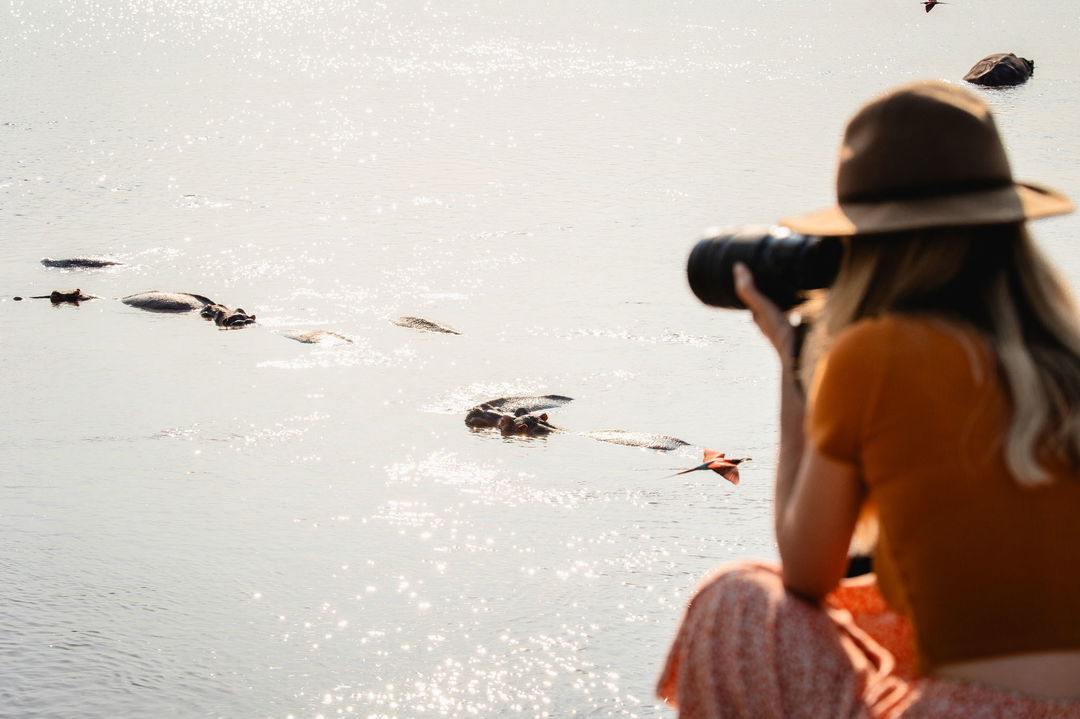 lady guest taking photos of hippos in pool by Puku Ridge Camp Zambia Luangwa Plains
