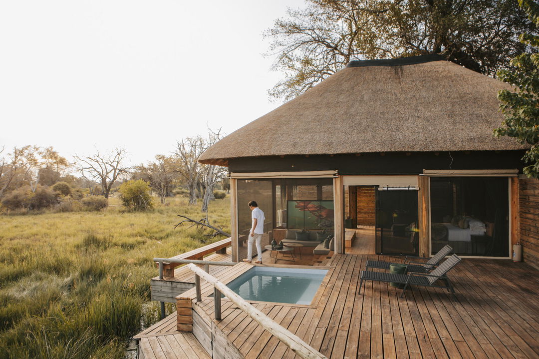 guest on deck next to splash pool of luxury room at Vumbura Plains Camp Wilderness Botswana Okavango Delta