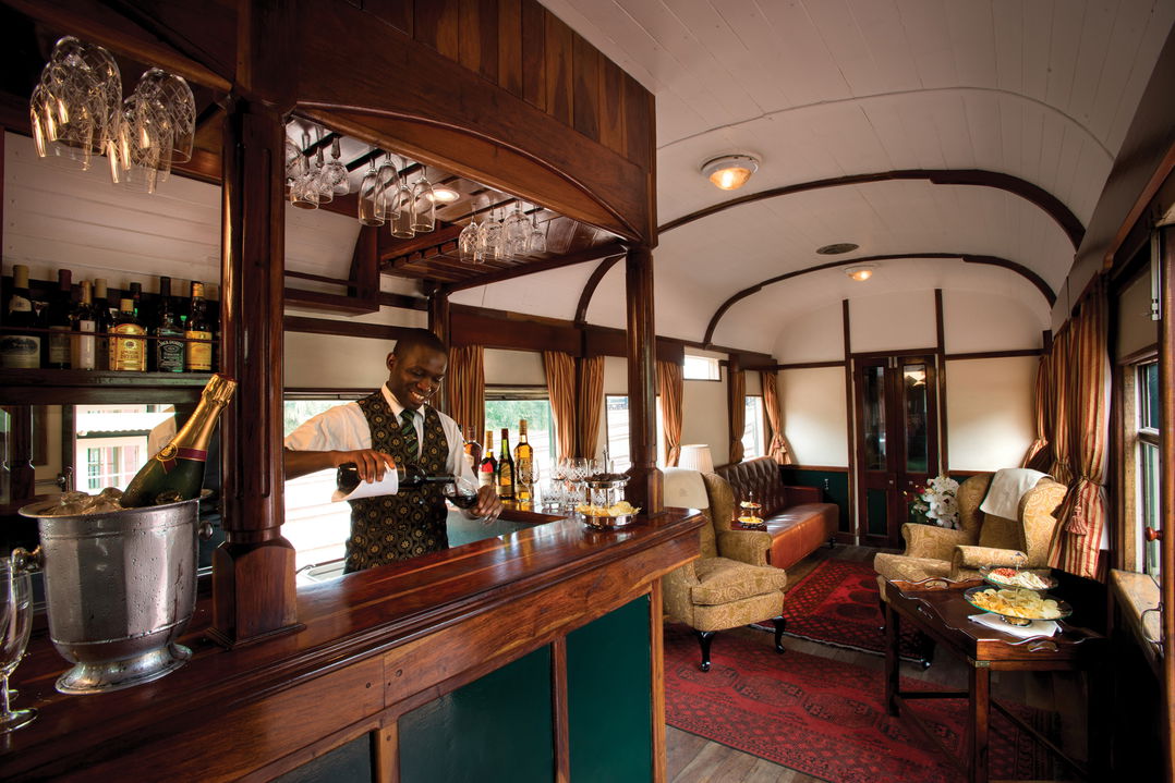 waiter serving drinks at bar section of Rovos rail luxury train safaris