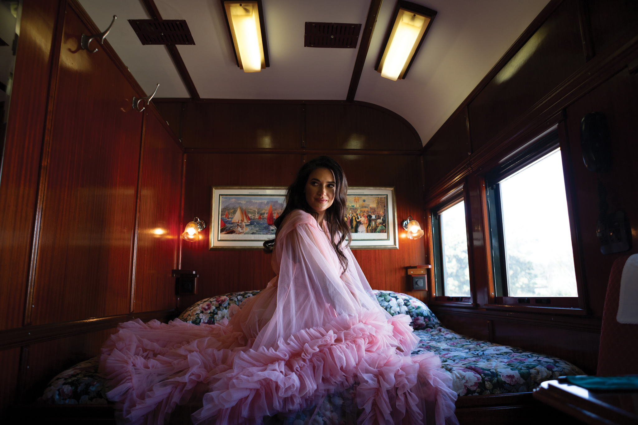 lady with pink dress siting on bed in cabin of Rovos rail luxury train safaris