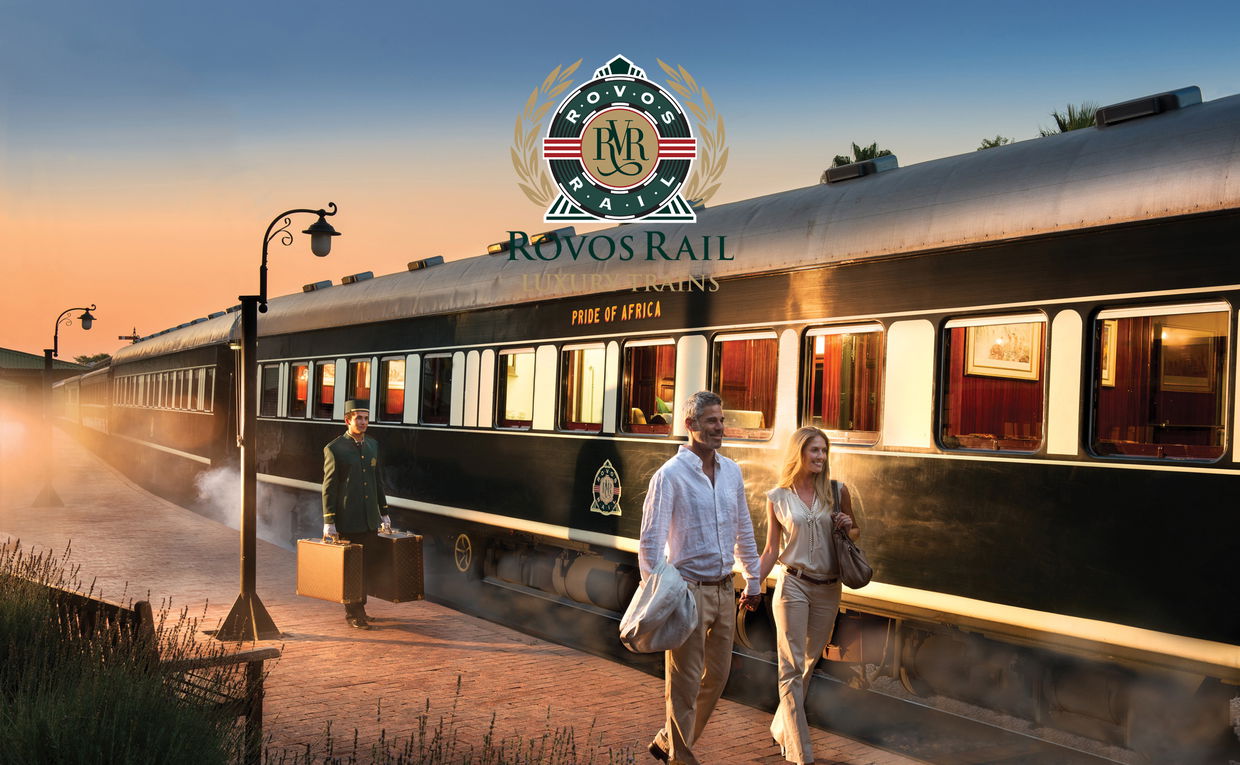 couple walking to front of train on platform with Rovos rail luxury train safaris with logo overlay