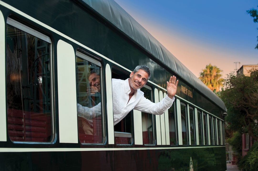 guest waving from train cart on platform with Rovos Rail Luxury Trains