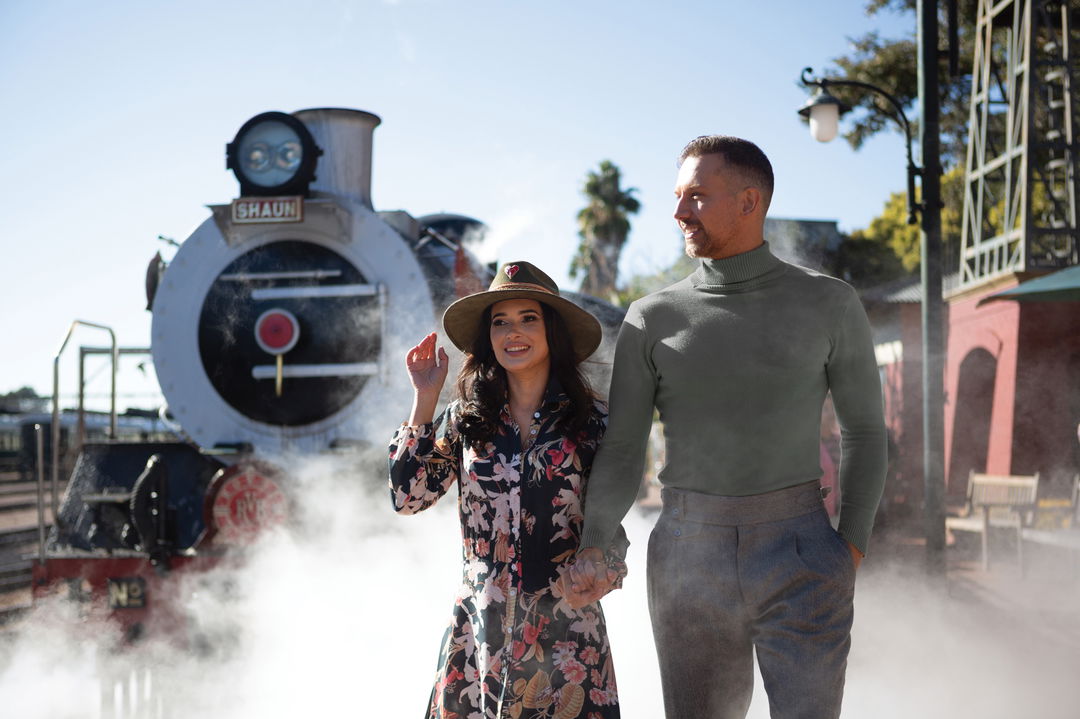 couple holding hands in front of steam train ready to depart at Rovos rail luxury train safaris