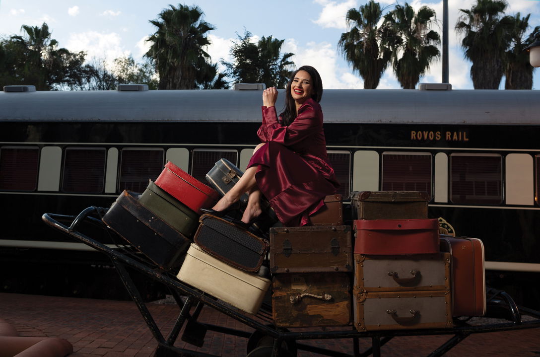 lady sitting on luggage on the platform of station at Rovos rail luxury train safaris