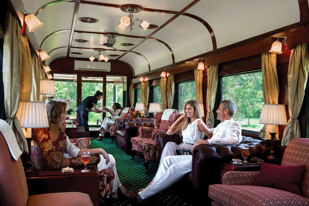 guests enjoying drinks in the lounge area of observation cart of Rovos rail luxury train safaris