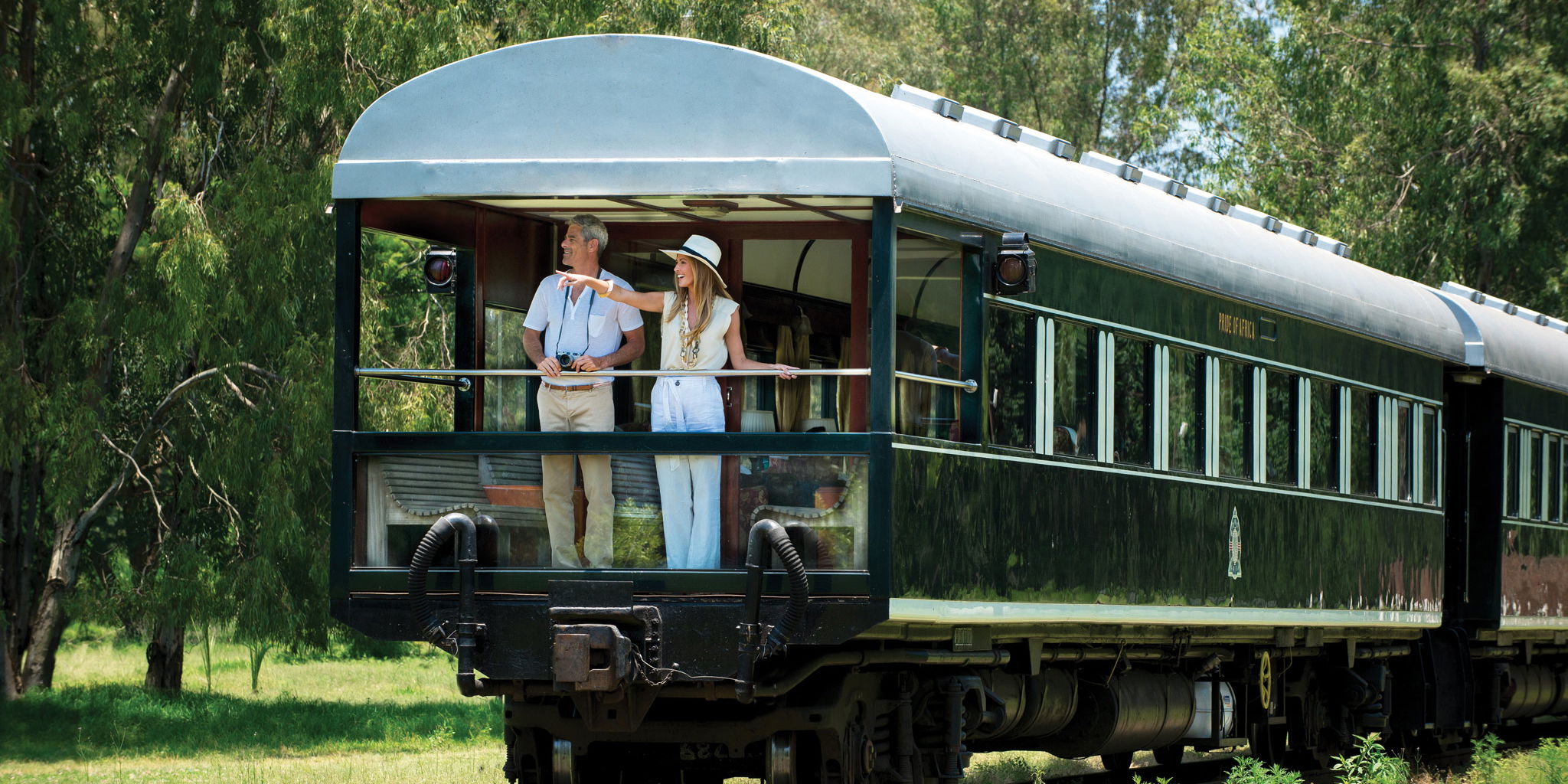 Couple standing in back of train cart waiting to depart at Rovos rail train company