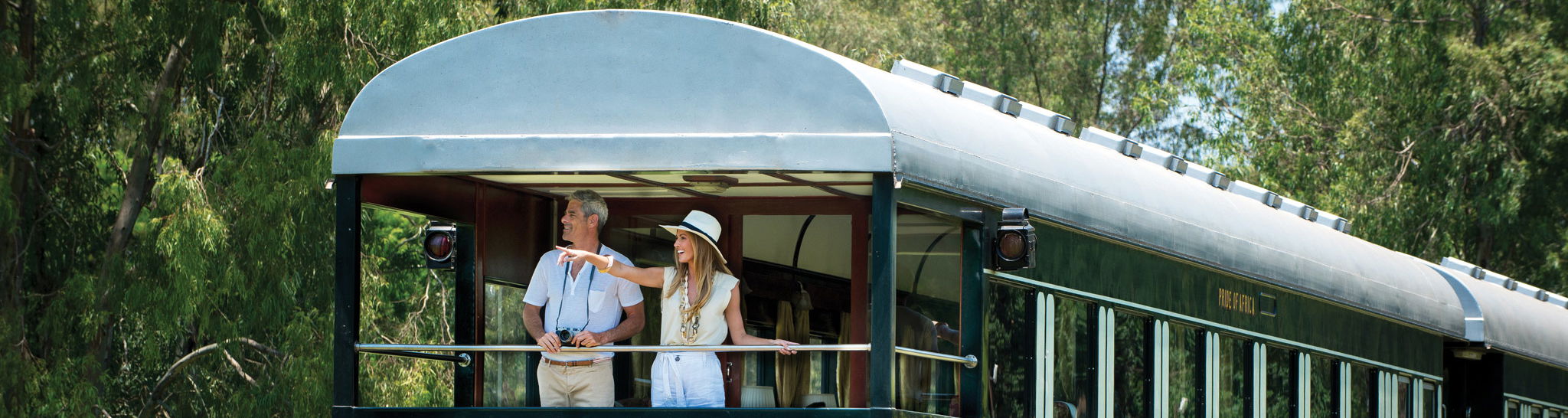 Couple standing in back of train cart waiting to depart at Rovos rail train company