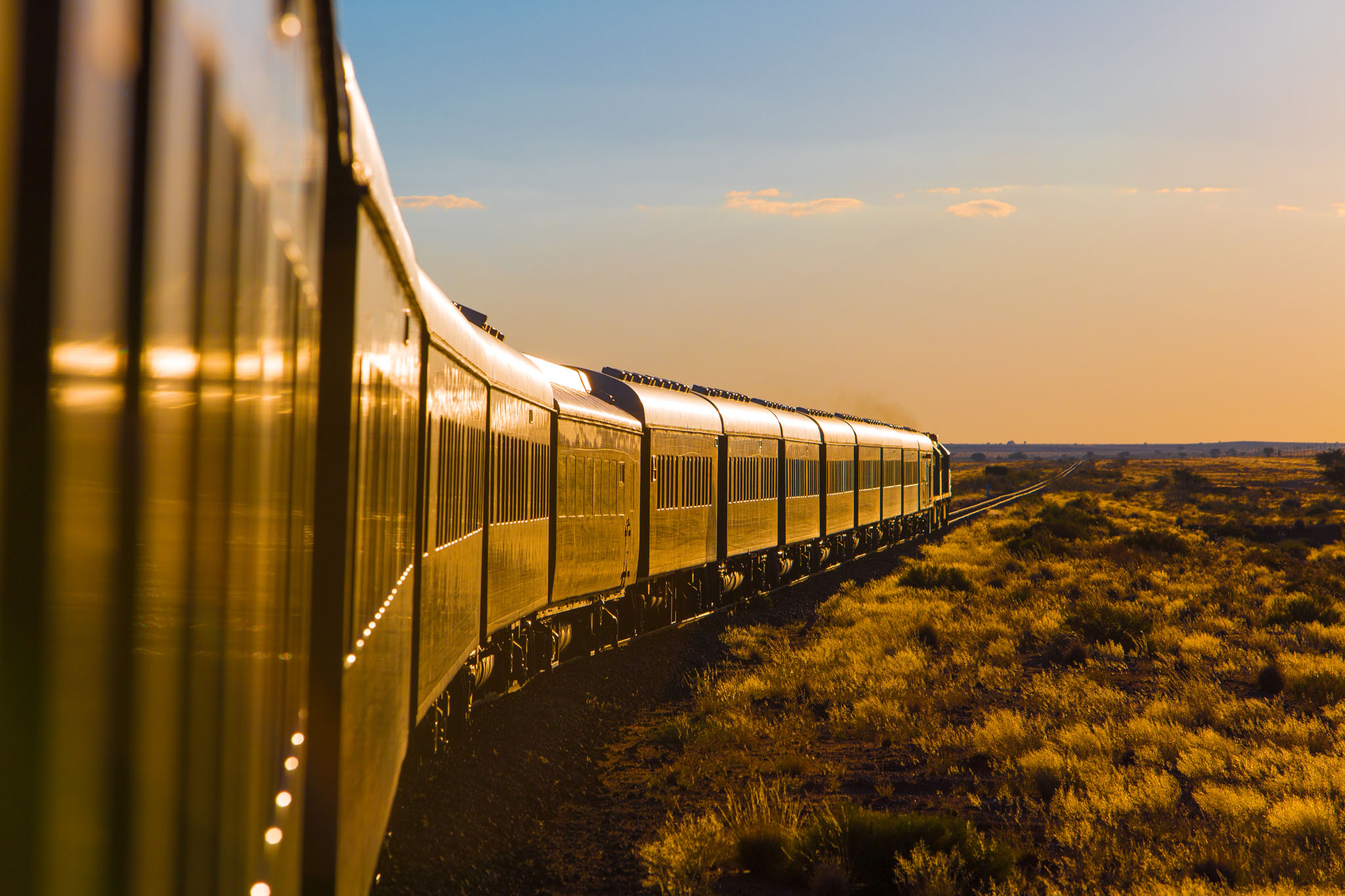 train snaking through countryside in south Africa with big mountains backdrop at Rovos rail luxury train safaris