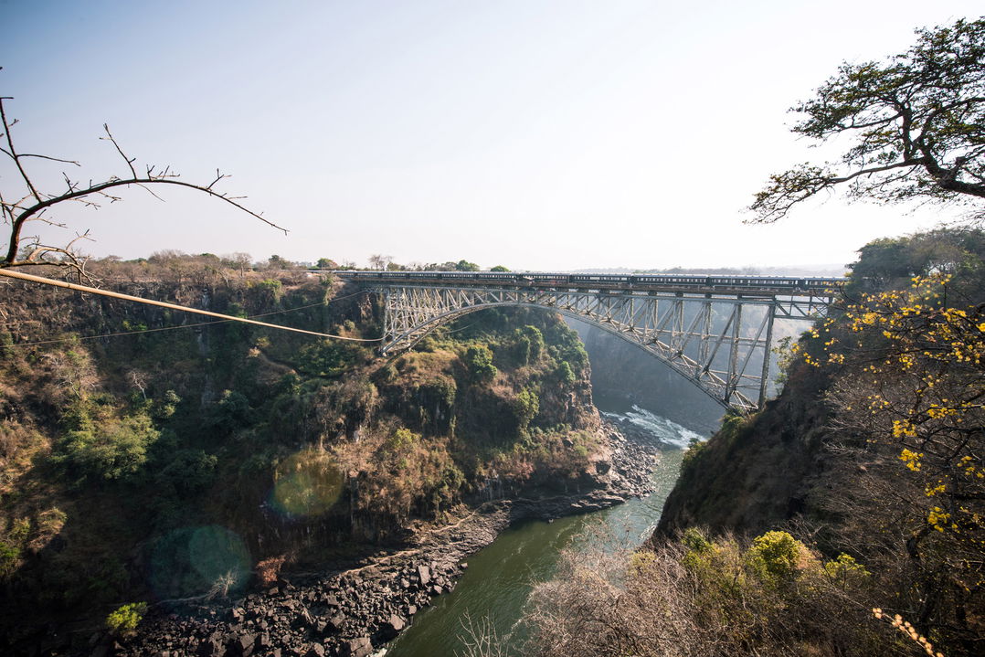 train on Victoria falls bridge over river in Zimbabwe with Rovos rail luxury train safaris