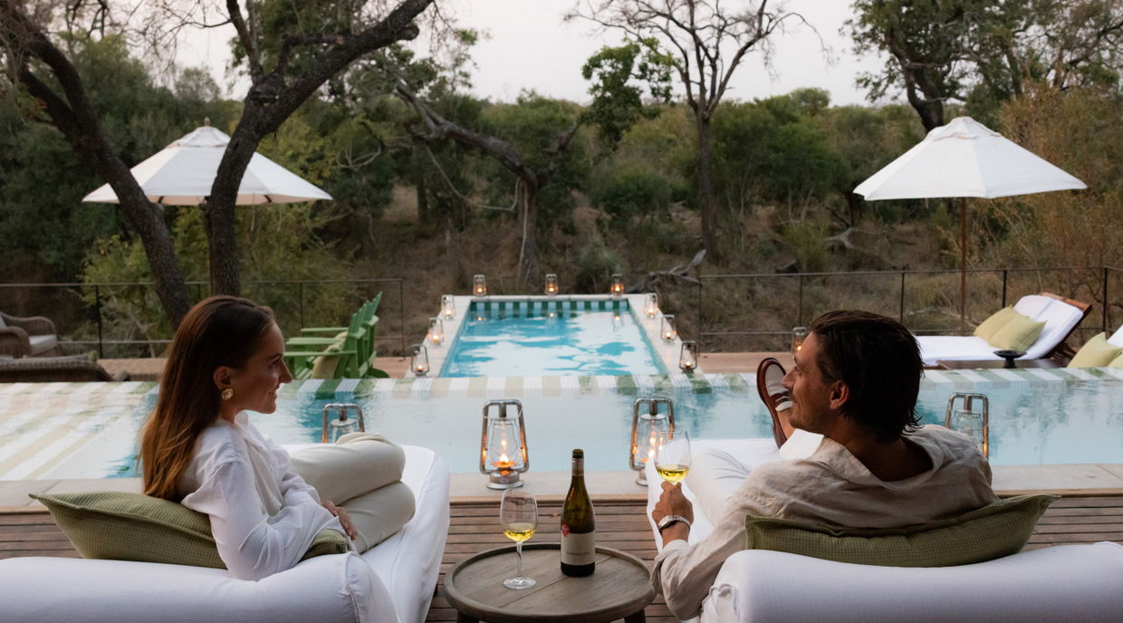 couple having sundowners on pool deck by Africa house royal malewane