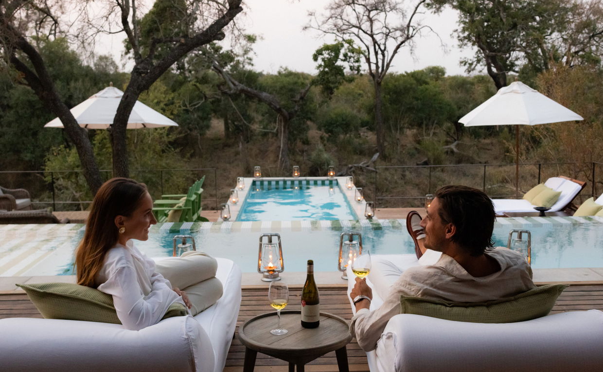 couple having sundowners on pool deck by Africa house royal malewane couple having sundowners on pool deck by Africa house royal malewane