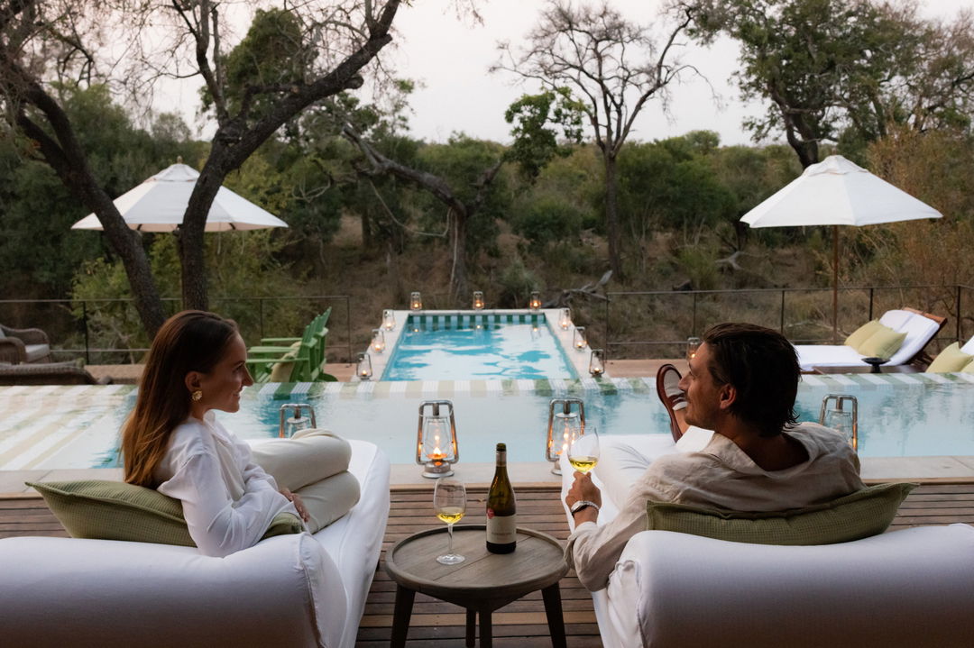 couple having sundowners on pool deck by Africa house royal malewane