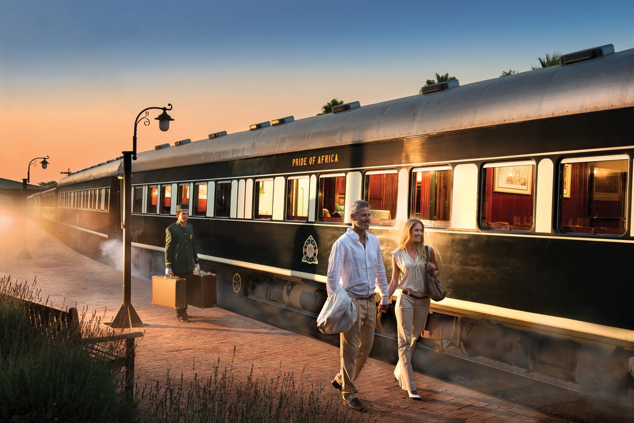 couple walking next to rovos rail at station