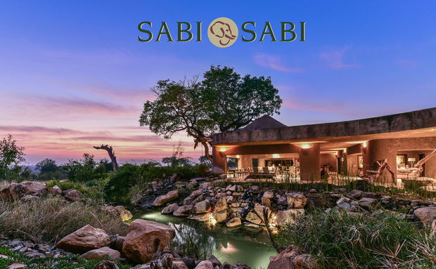 Exterior evening view of sabi sabi earth lodge with logo