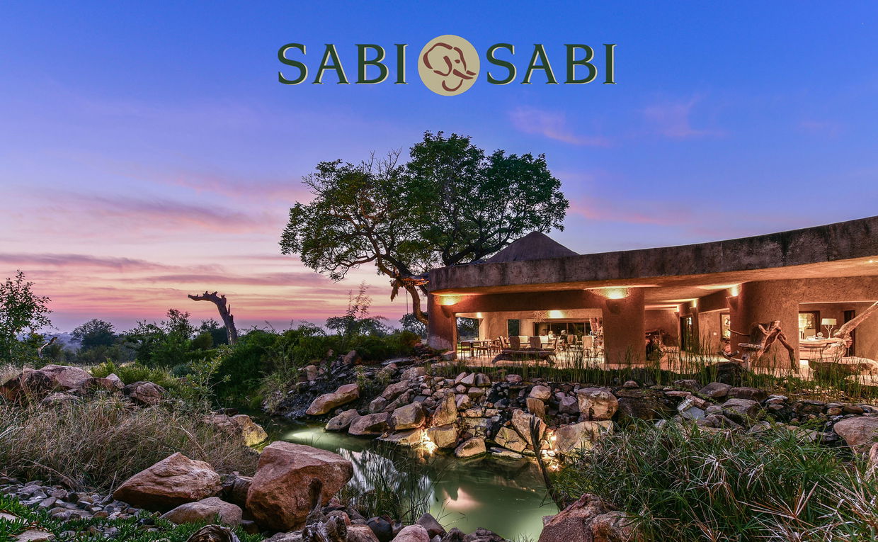 Exterior evening view of sabi sabi earth lodge with logo Exterior evening view of sabi sabi earth lodge with logo