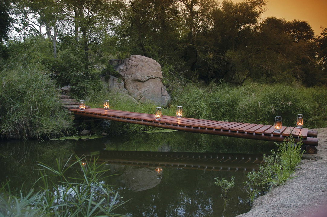 bridge with lanterns over pond at sabi sabi litlle bush camp