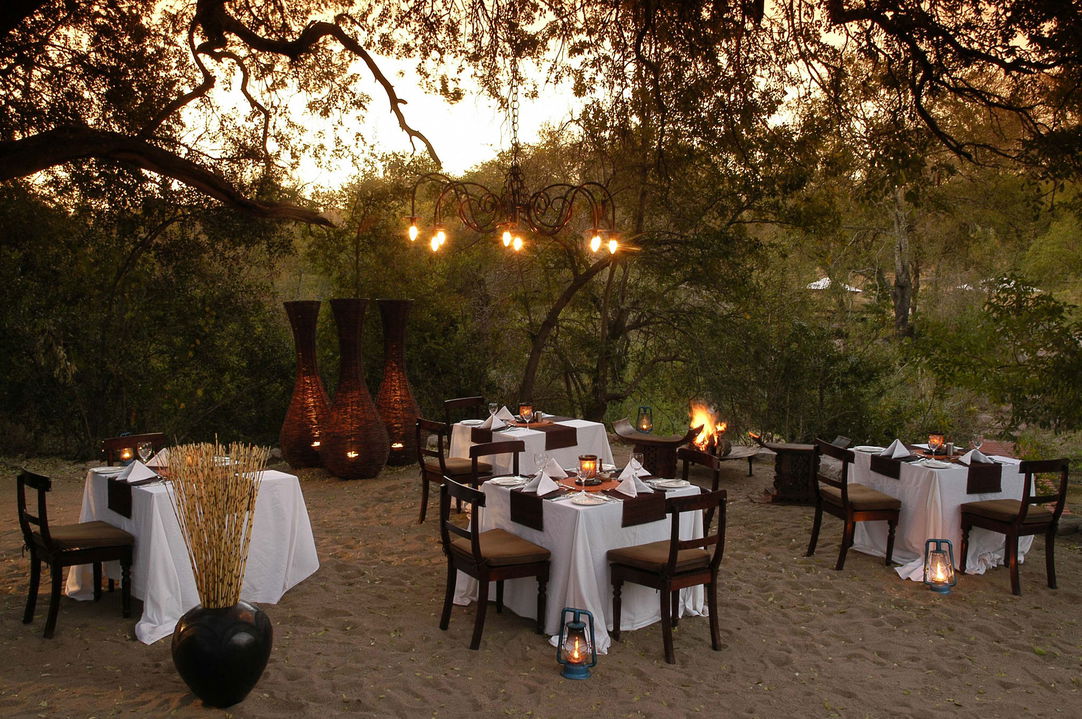 dinner tables set in boma at sunset by lillte bush camp sabi sabi
