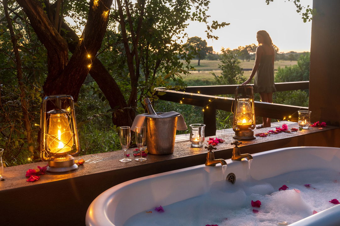 bathtub viewed from bathroom of LM honeymoon suite and lady on deck beyond at selati camp sabi sabi