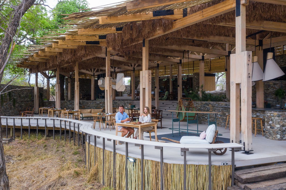 guests sitting at table on viewing deck of Saseka tented camp Thornybush