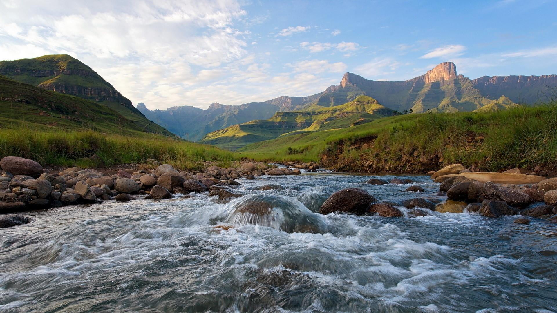 stream flowing in valley surrounded by Drakensberg Mountains