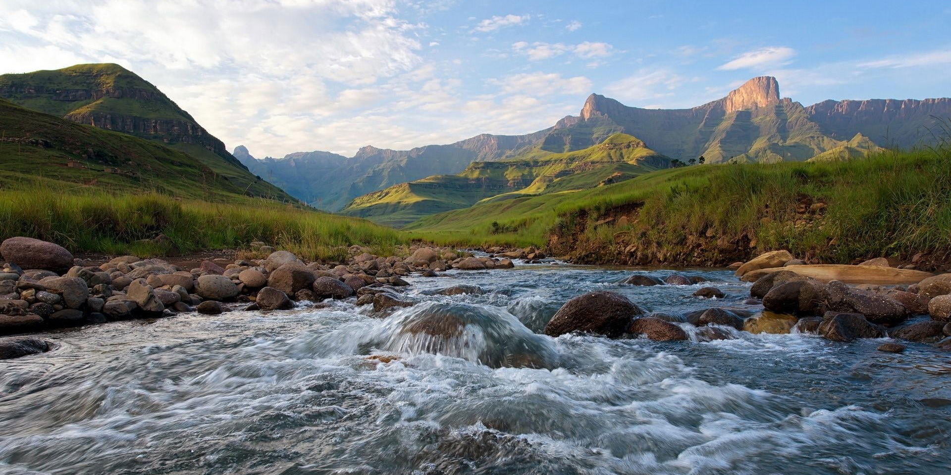 stream flowing in valley surrounded by Drakensberg Mountains