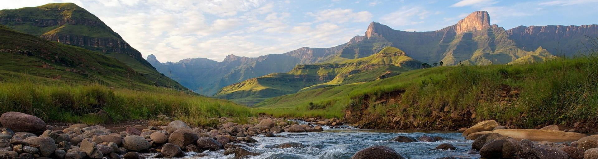 stream flowing in valley surrounded by Drakensberg Mountains
