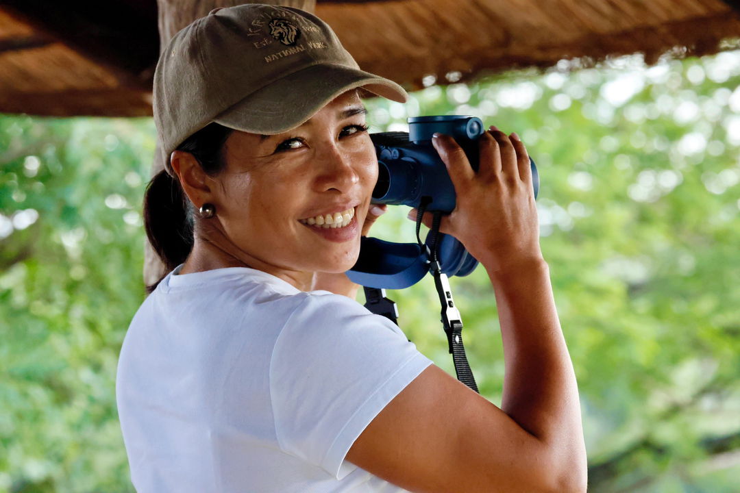 smiling lady holding binoculars on a birding safari Kruger national park