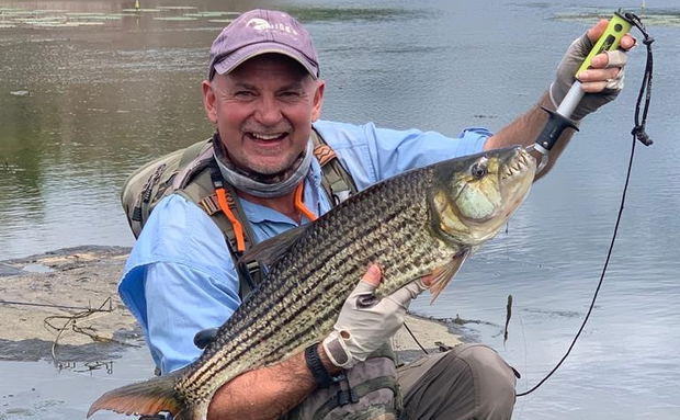 Fly fisherman holding big tigerfish caught on fly in Komati river Kruger national park