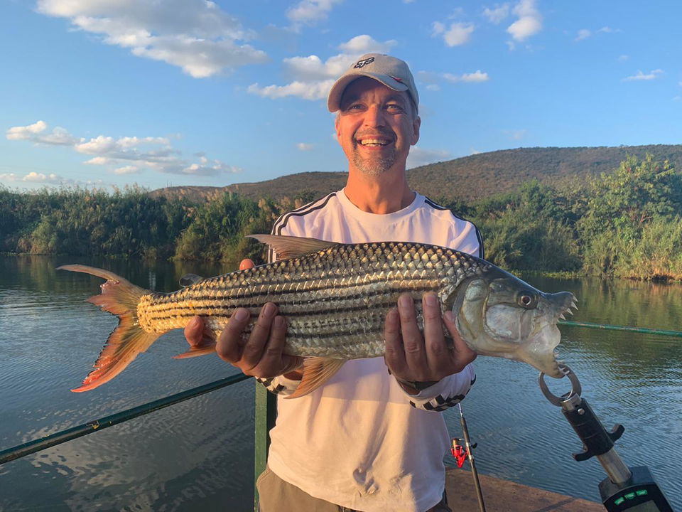 young man holding a tigerfish with lip grabber caught on the Komati river Kruger national park