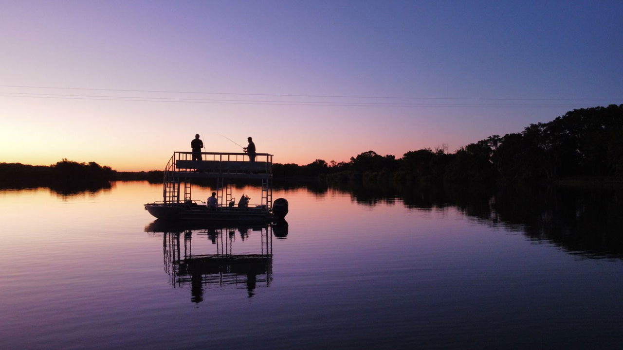 sunset view of barge on Komati river with two fisherman