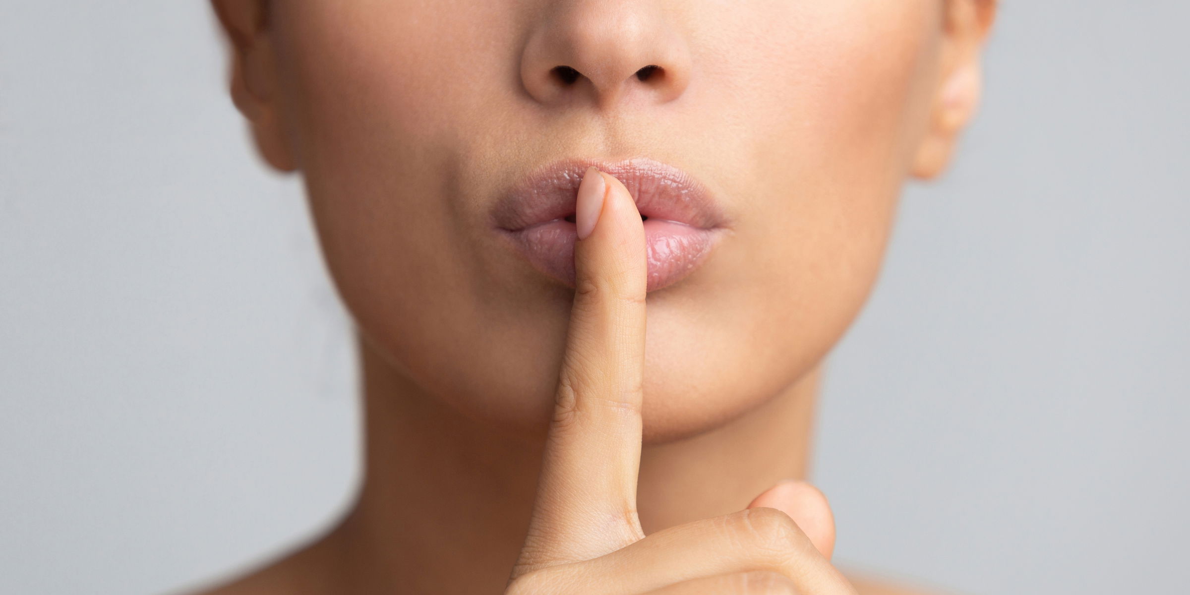 woman with finger on lip signalling to keep quiet