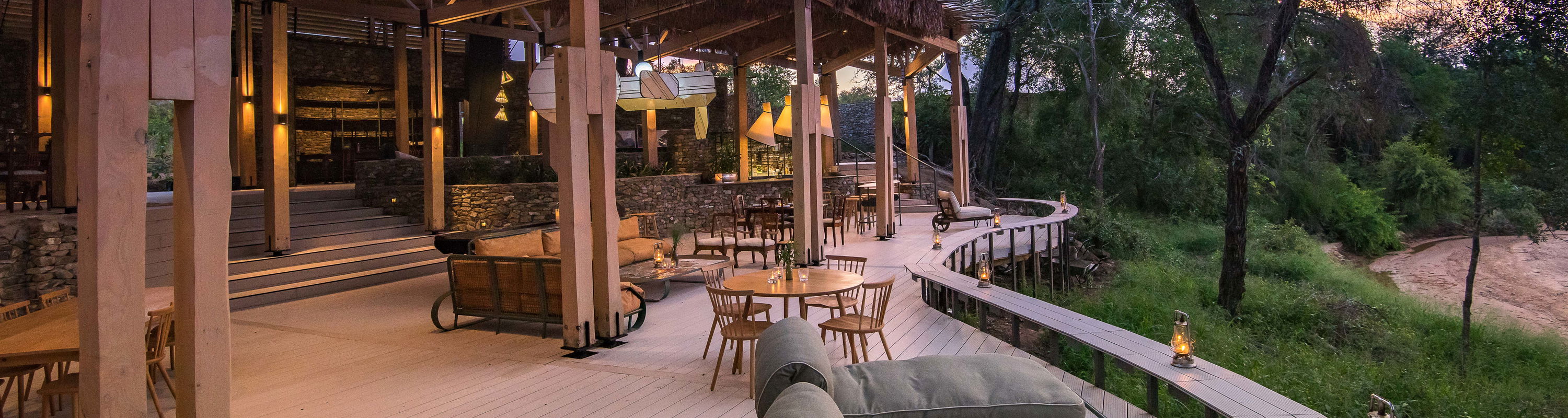 view of the deck and entertainment area of main lodge at thornybush safaris at sunset