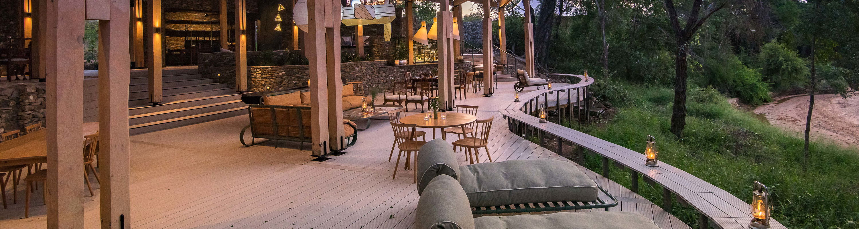 view of the deck and entertainment area of main lodge at thornybush safaris at sunset