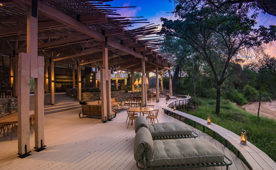 view of the deck and entertainment area of main lodge at thornybush safaris at sunset