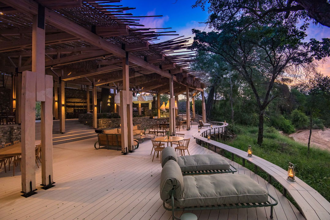 view of the deck and entertainment area of main lodge at thornybush safaris at sunset
