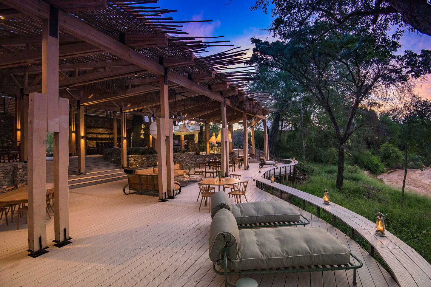 view of the deck and entertainment area of main lodge at thornybush safaris at sunset