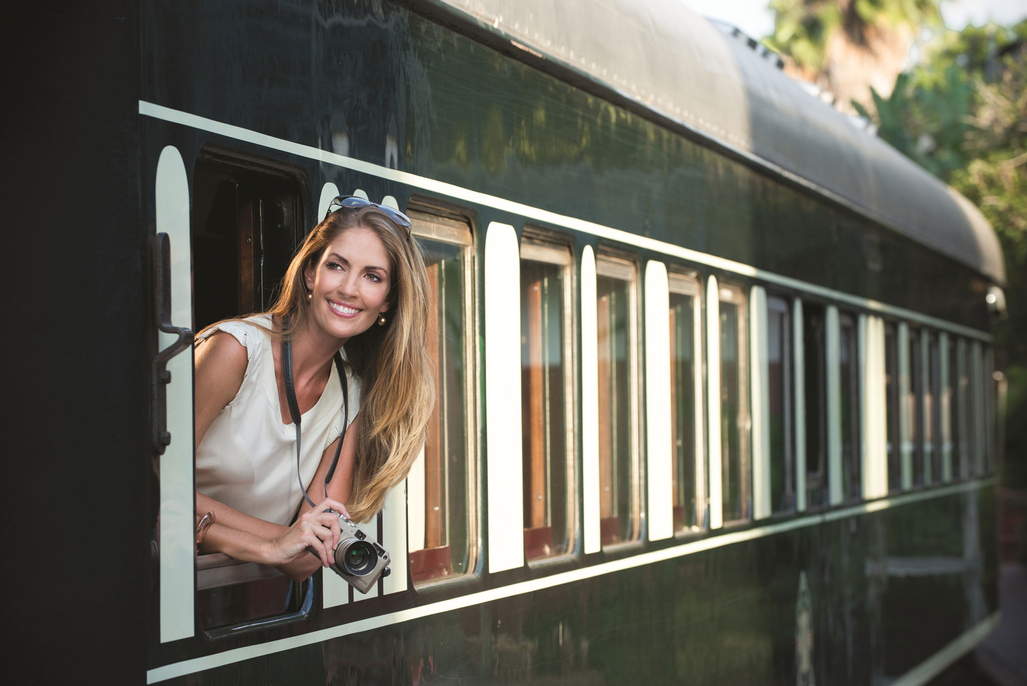 smiling lady with camera looking out from train cart ready to depart at Rovos rail luxury train safaris