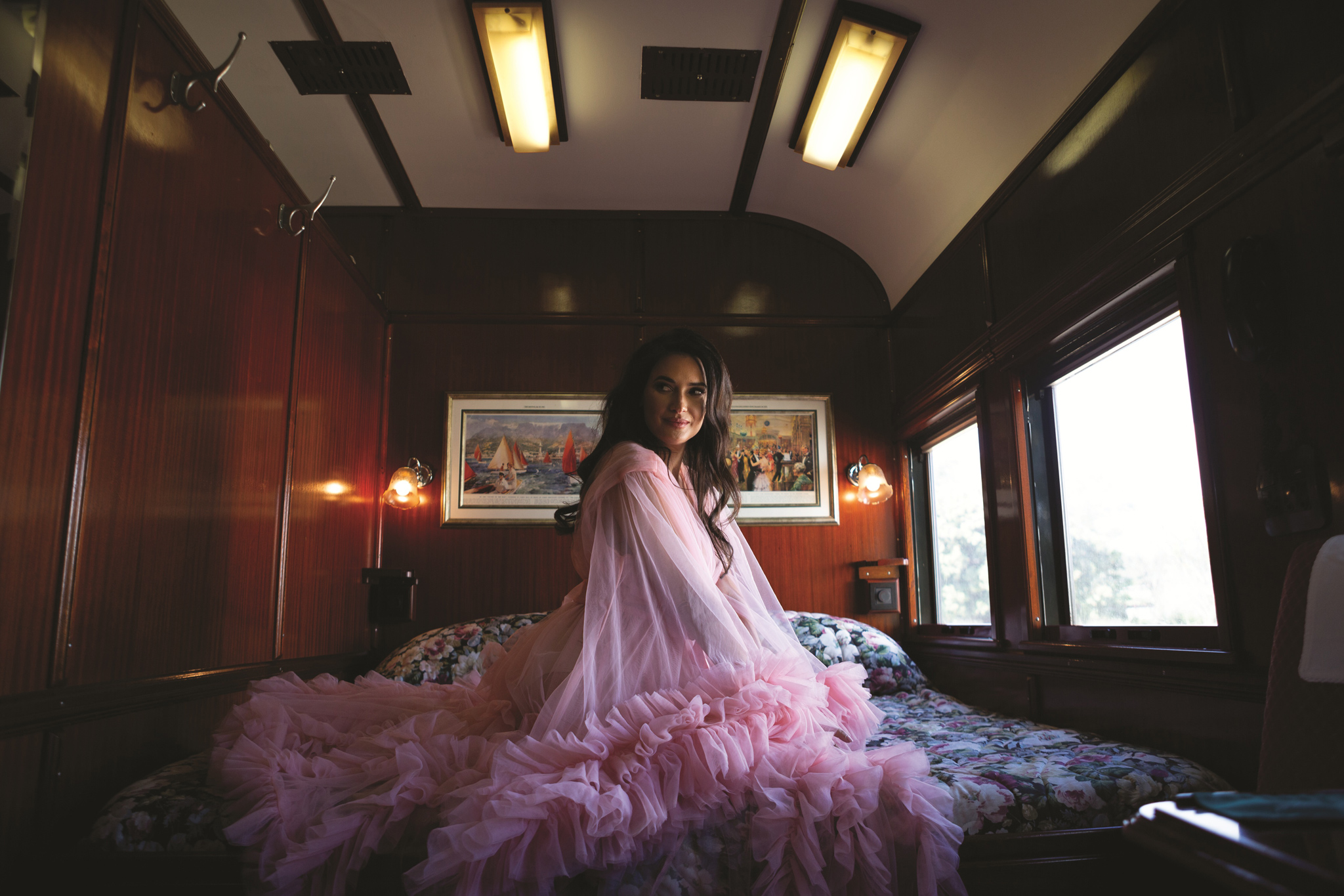 lady with pink dress siting on bed in cabin of Rovos rail luxury train safaris