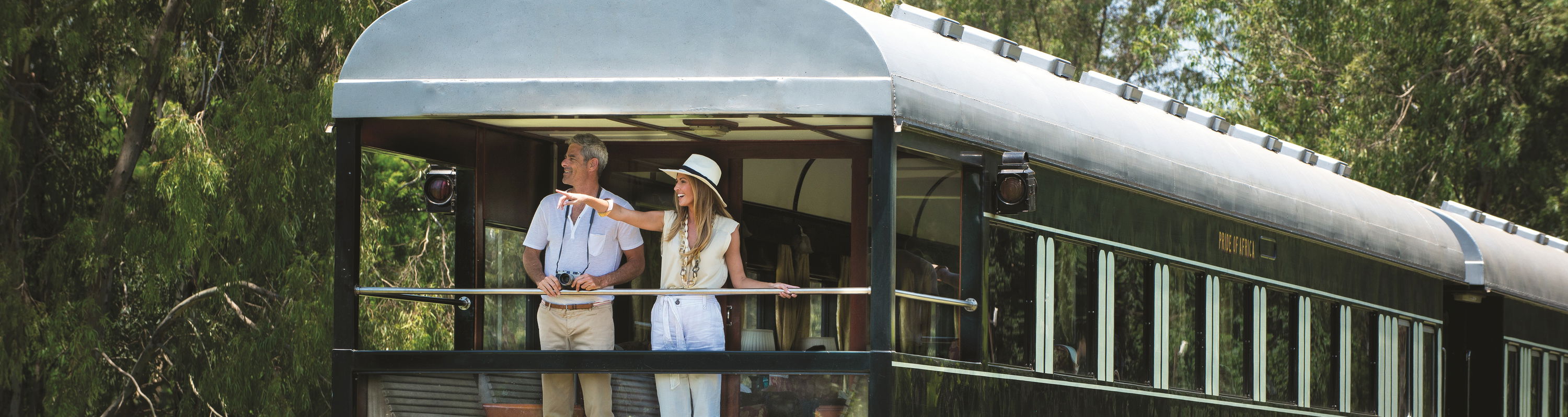 Couple standing in back of train cart waiting to depart at Rovos rail train company